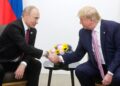 Putin and Trump shake hands, sitting side by side in a file photo.